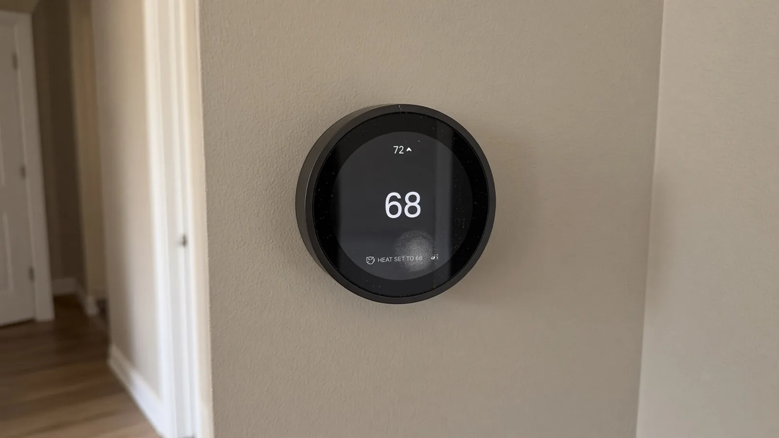Wall-mounted home thermostat in a hallway, photographed on a phone
